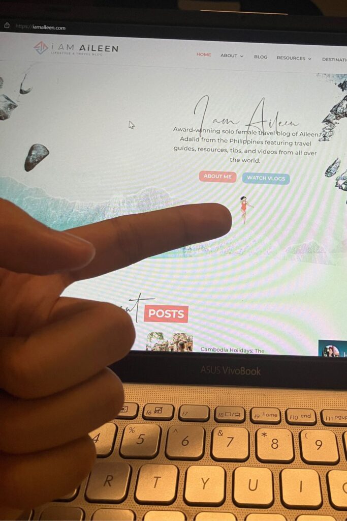My laptop screen displays the homepage of I Am Aileen