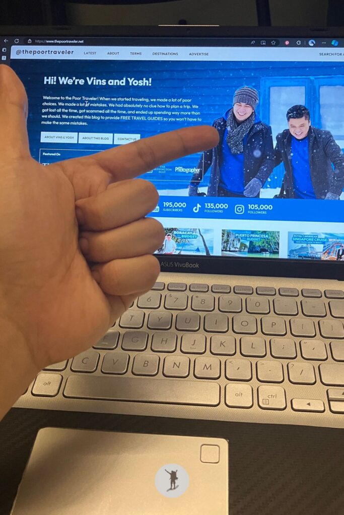 My laptop screen displays the homepage of ThePoorTraveler