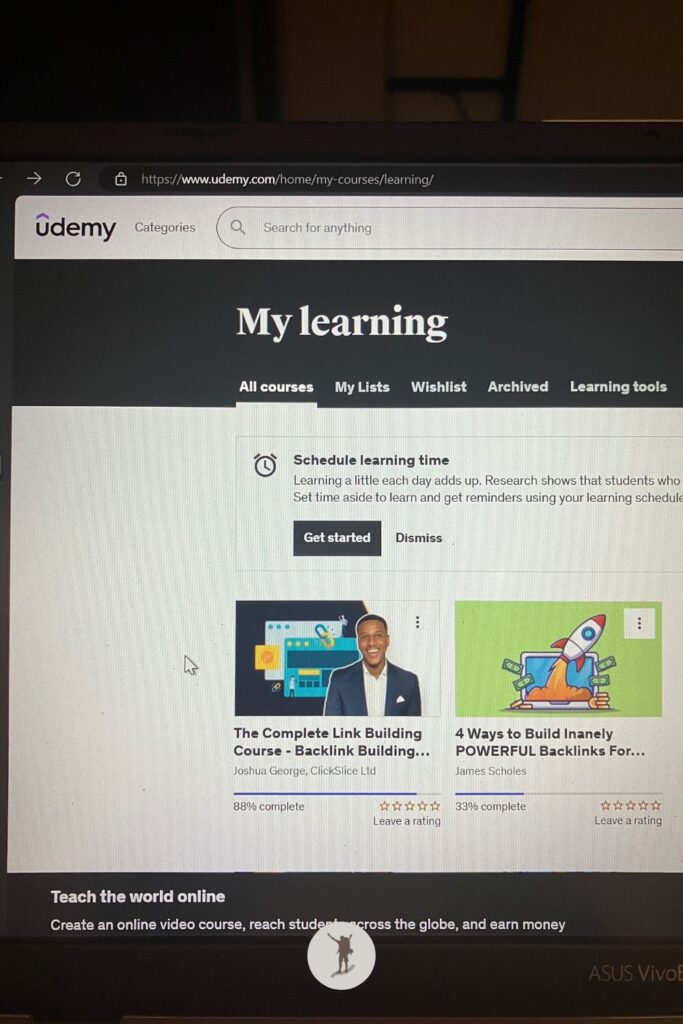 My laptop screen shows my Udemy courses, including the link-building course