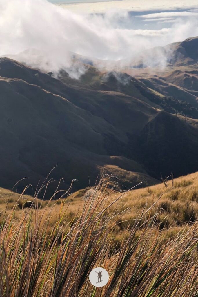 The view of the grasslands with rain clouds touching the rolling hills at Mount Pulag