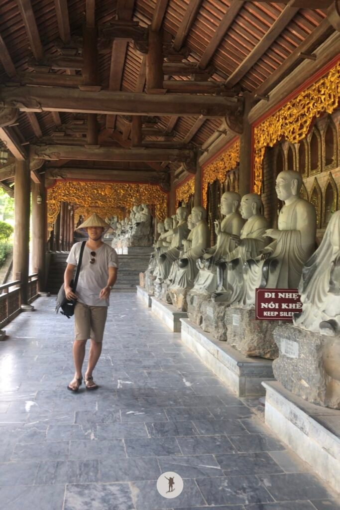 A very long covered pathway lined with statues of the enlightened followers of Buddha in Bai Dinh Pagoda, Ninh Binh, Vietnam