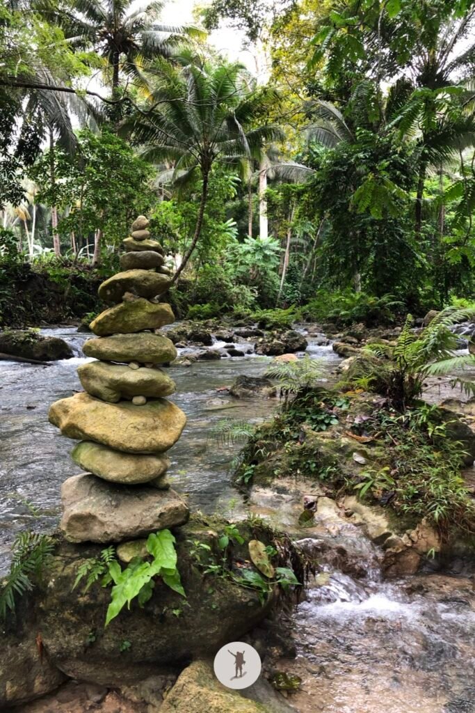 Idyllic jungle view with stone stack near the exit of Kawasan Falls after canyoneering, Cebu, Philippines