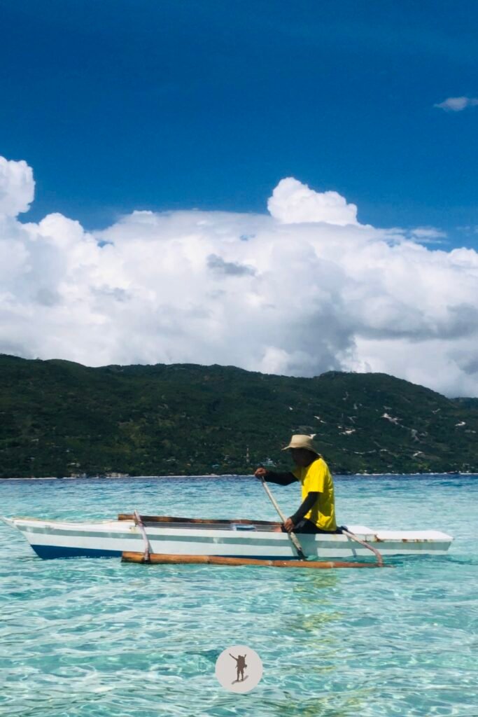 Our Beautiful Experience Visiting Sumilon Island After Whale Shark Watching in Oslob 25 A fisher man gliding on the crystal clear water of Sumilon Island, Oslob, Cebu, Philippines