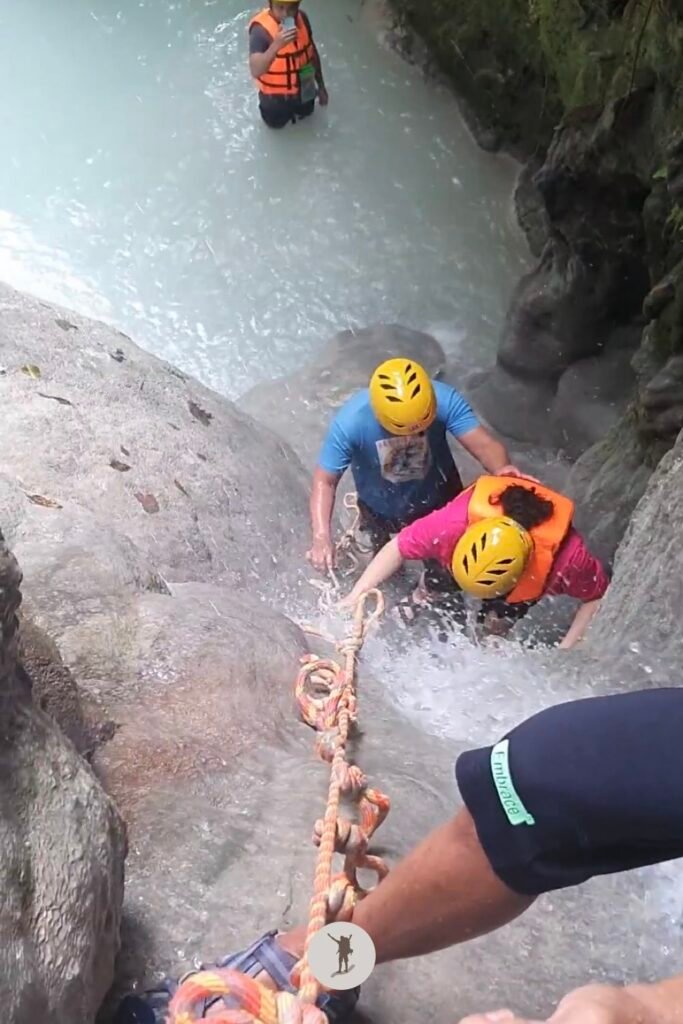 Our guide applying force to the back of my friend so she could easily climb the steep cascades at Aguinid Falls, Cebu, Philippines