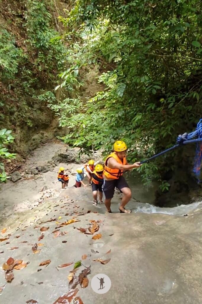 Part 1, a photo of me climbing a massive rock with a steep slope, using the water to reach the top in Aguinid Falls, Cebu, Philippines