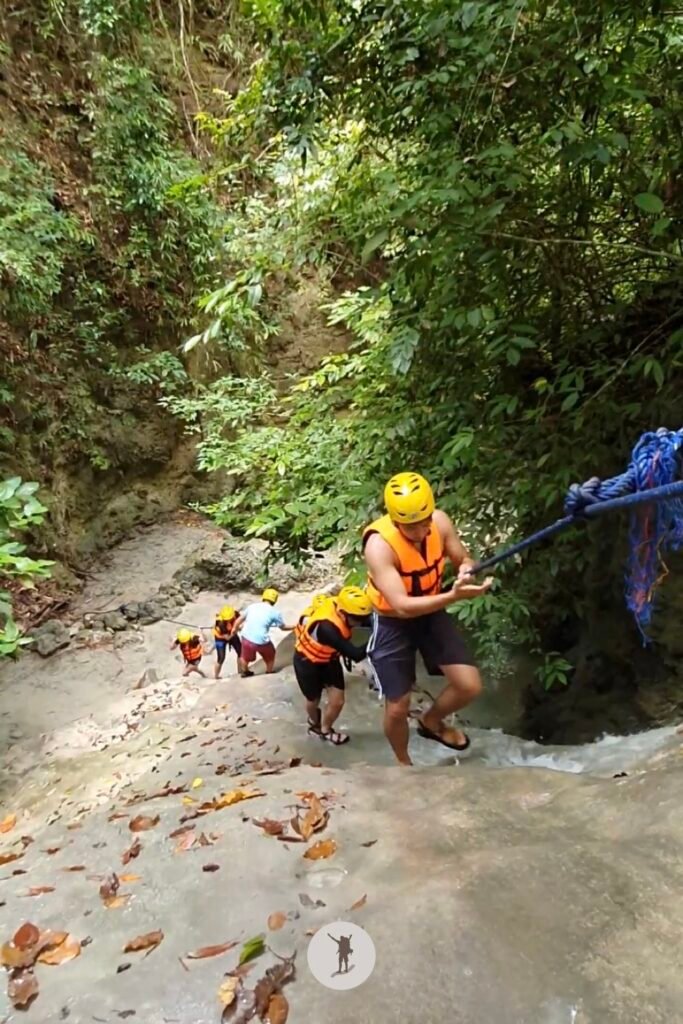 Part 2, a photo of me climbing a massive rock with a steep slope, using the water to reach the top in Aguinid Falls, Cebu, Philippines