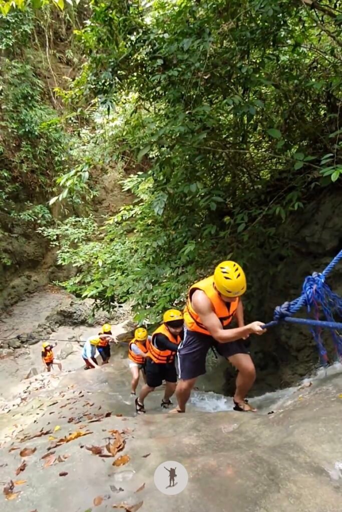 Part 3, a photo of me climbing a massive rock with a steep slope, using the water to reach the top in Aguinid Falls, Cebu, Philippines