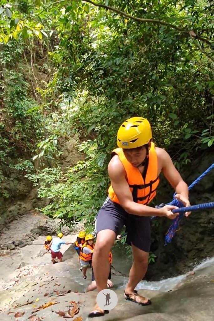 Part 4, a photo of me climbing a massive rock with a steep slope, using the water to reach the top in Aguinid Falls, Cebu, Philippines