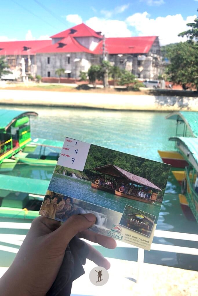 Our Unforgettable 5-Day Central Visayas Trip That You Can Easily Follow For Your Trip 4 A picture of my hand holding the ticket with Loboc River and Loboc Church in the background, Bohol, Philippines